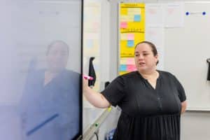 woman in black dress standing in front of a LED screen